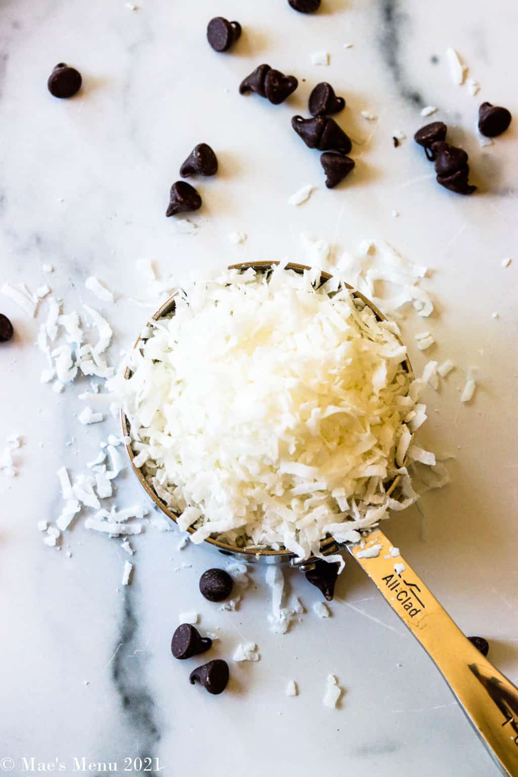 An overhead shot of a measuring cup of sweetened shredded coconut with chocolate chips