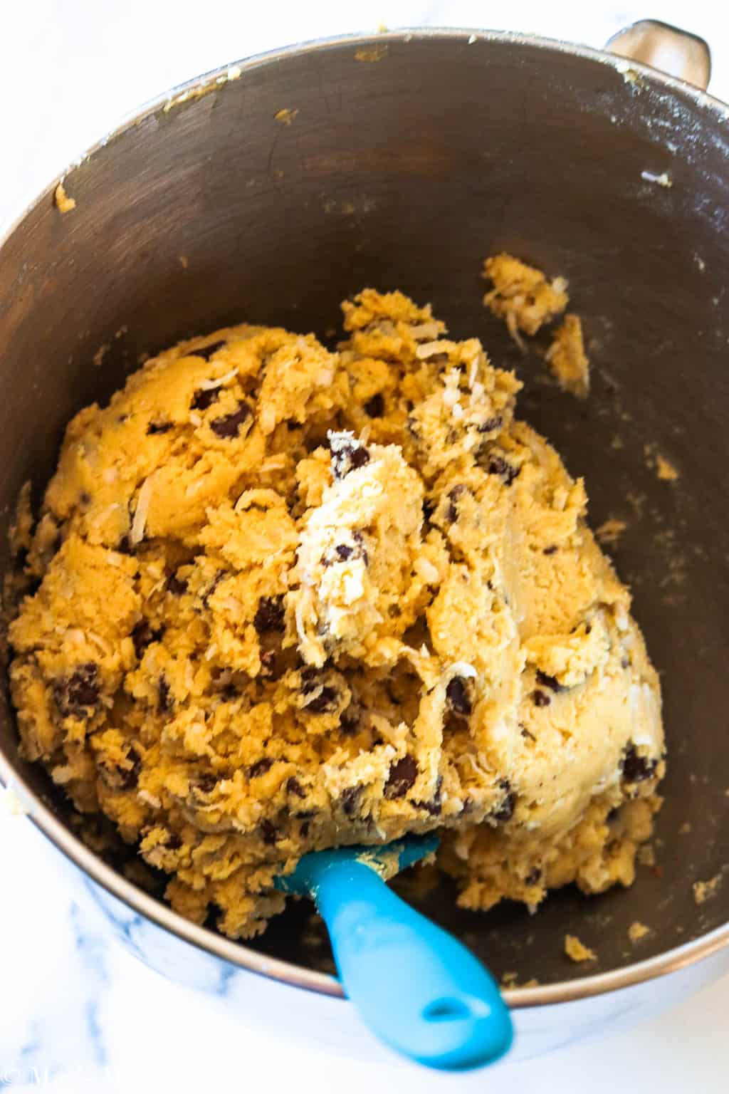 A mixing bowl of chocolate chip coconut cookie dough