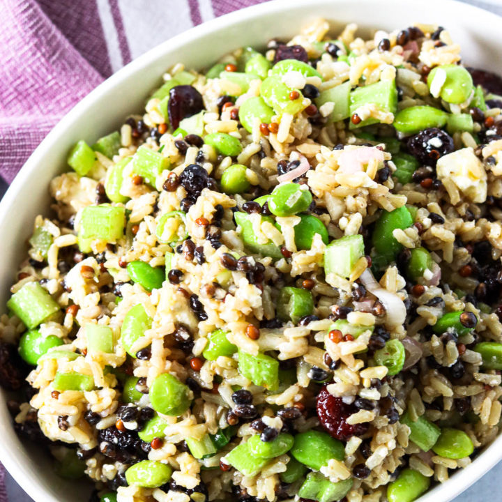 An overhead shot of a small white bowl of cranberry and edamame brown rice salad