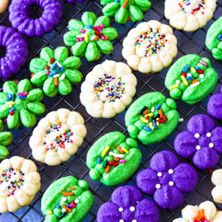 Purple, green, and white cream cheese spritz cookies on a cooking rack