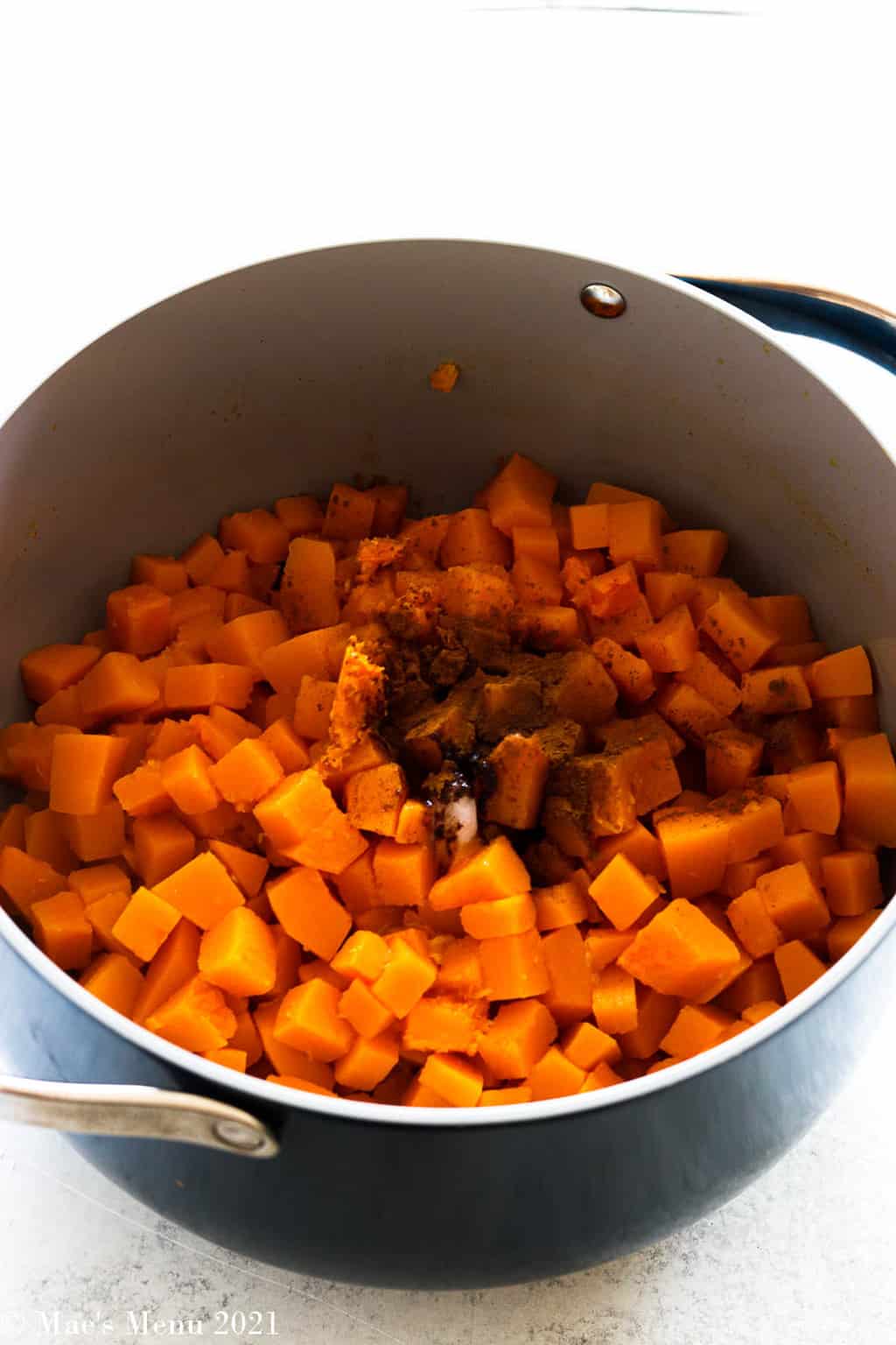 A side shot of a pot of butternut squash with the seasonings on top