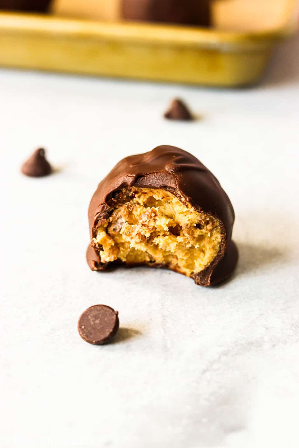 An up-close side shot of a peanut butter bon bon with a bite taken out of it