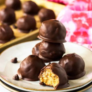 A stack of peanut butter bon bons on a small stack of plates. One bon bon has a bite taken out of it