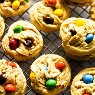 An up close overhead shot of piles of peanut butter M&M cookies on a cooling rack