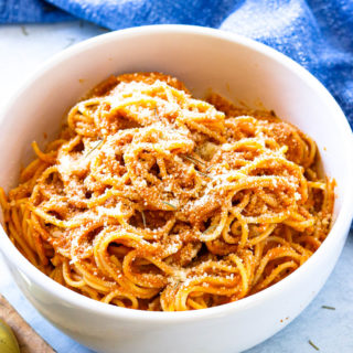 A large white bowl of pumpkin pasta sauce with shredded parmesan cheese on top