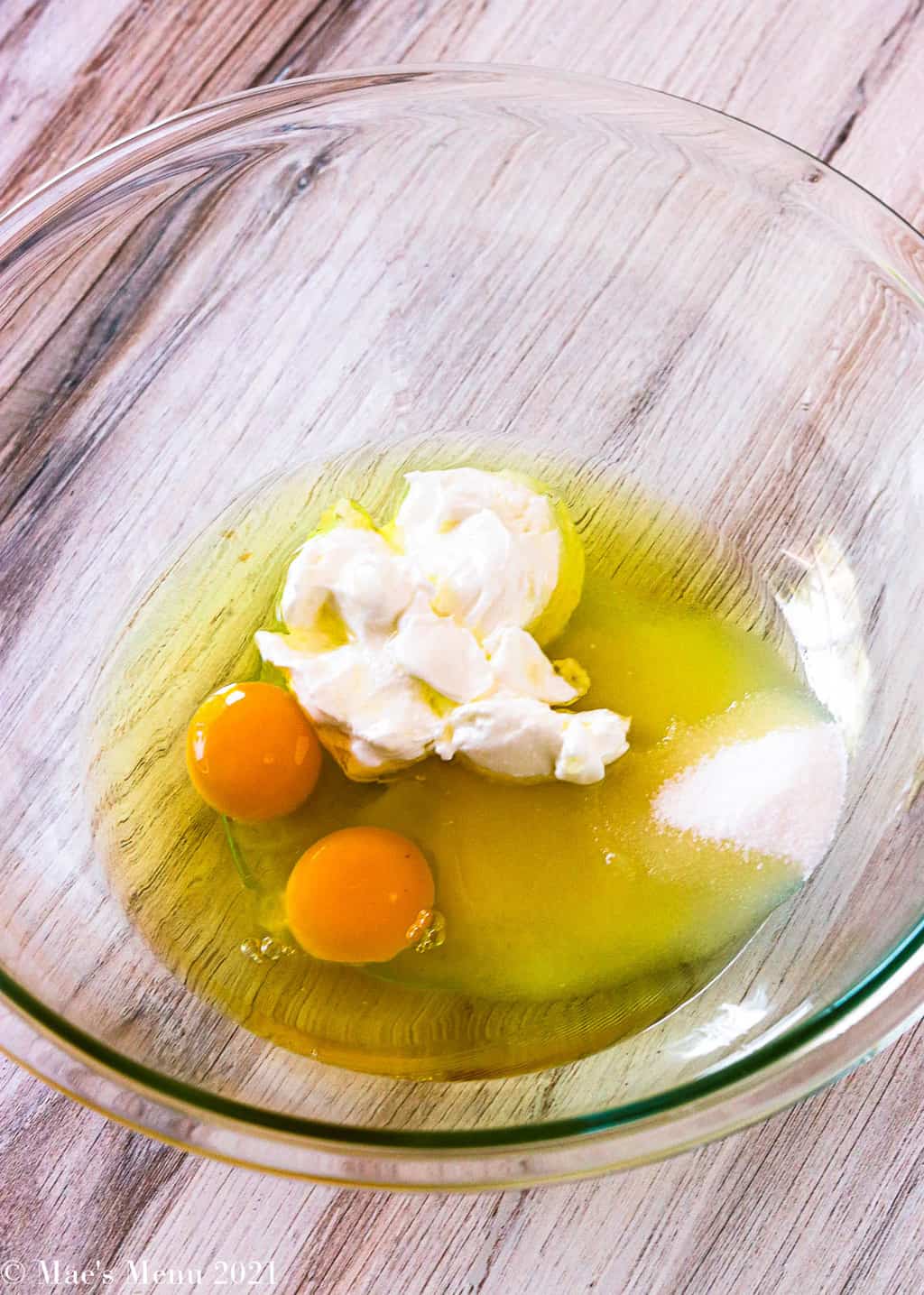 A large mixing bowl of eggs, sugar, greek yogurt, and avocado oil