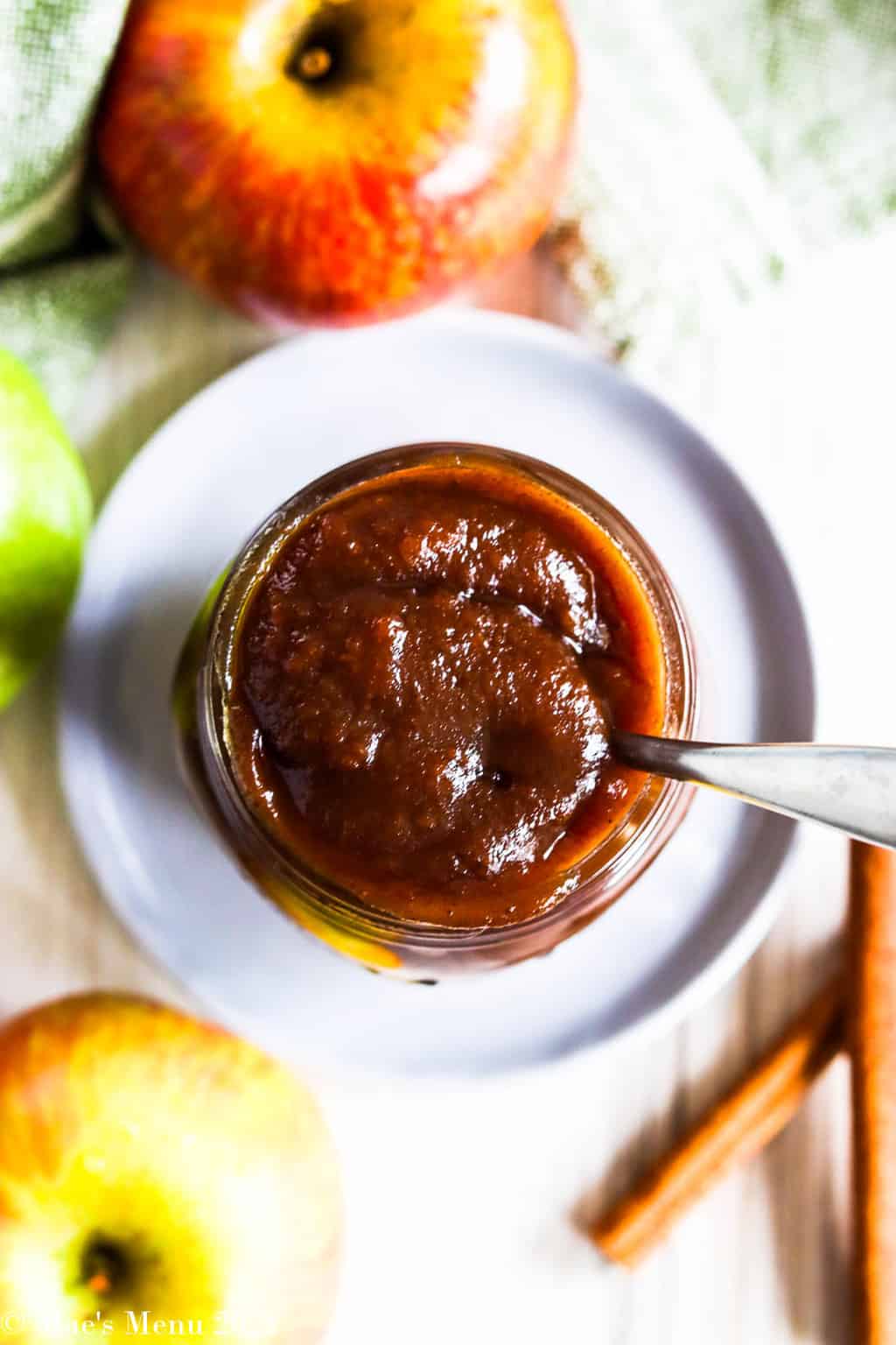 An up-close overhead shot of a ball jar of instant pot apple butter with a spoon in it