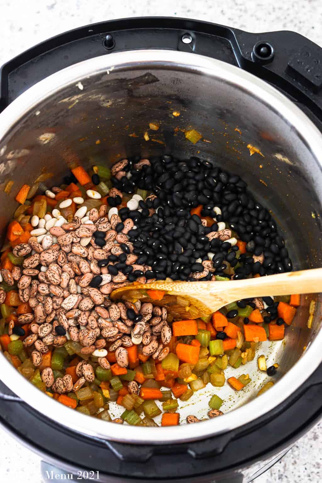 An overhead shot of am Instant pot with sauteed veggies and dried beans