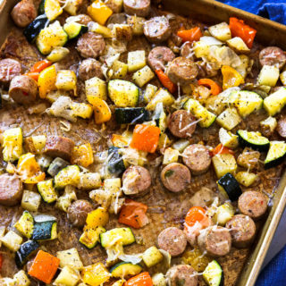 An overhead shot of a sheet pan of roasted sausage and veggies