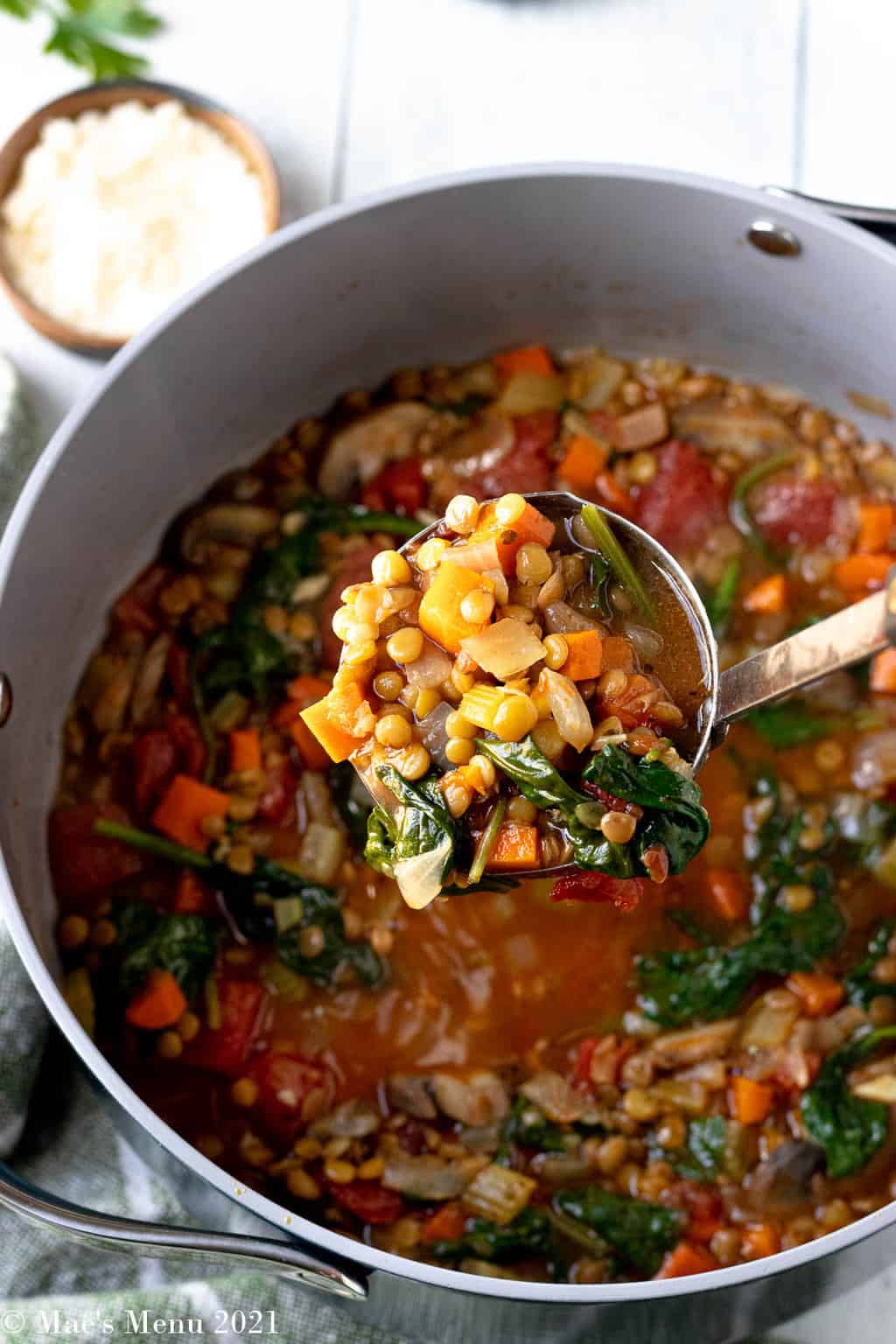 A ladle of Italian lentil soup over a pot of the soup