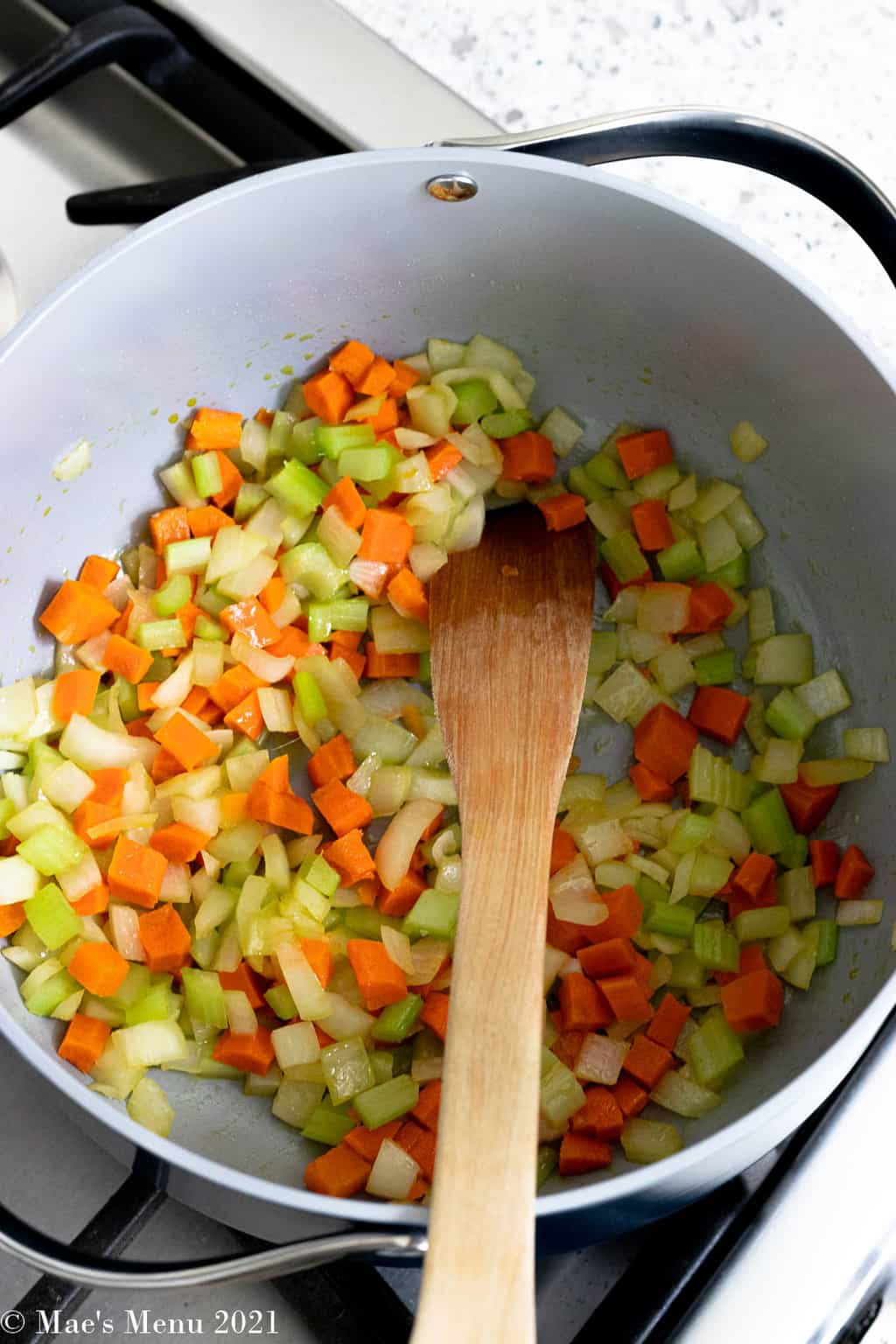 An overhead shot of a pan of onions, carrots, and celery