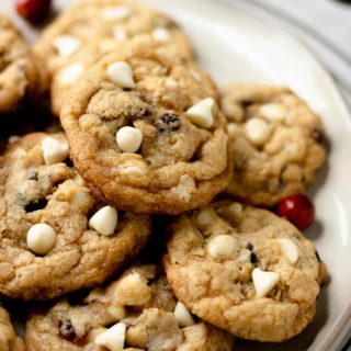 An up-close shot of a tan plate of white chocolate cranberry cookies