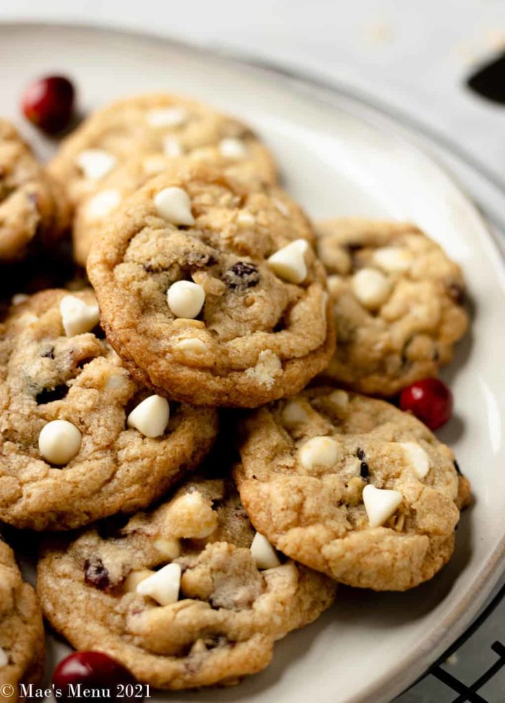 An up-close shot of a tan plate of white chocolate cranberry cookies