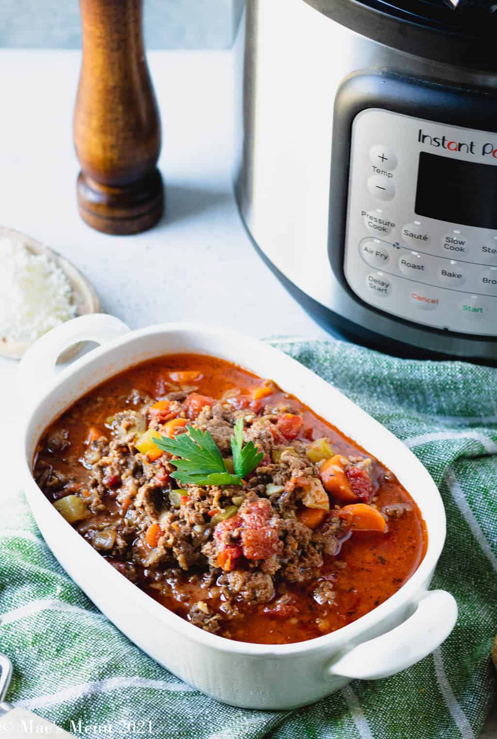 A large bowl of beef bolognese sauce next to a pressure cooker of it 