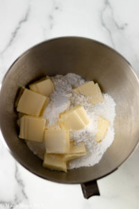 An overhead shot of a mixing bowl with confectioner's sugar and butter