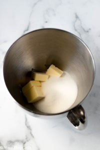 An overhead shot of a mixing bowl with butter and granulated sugar