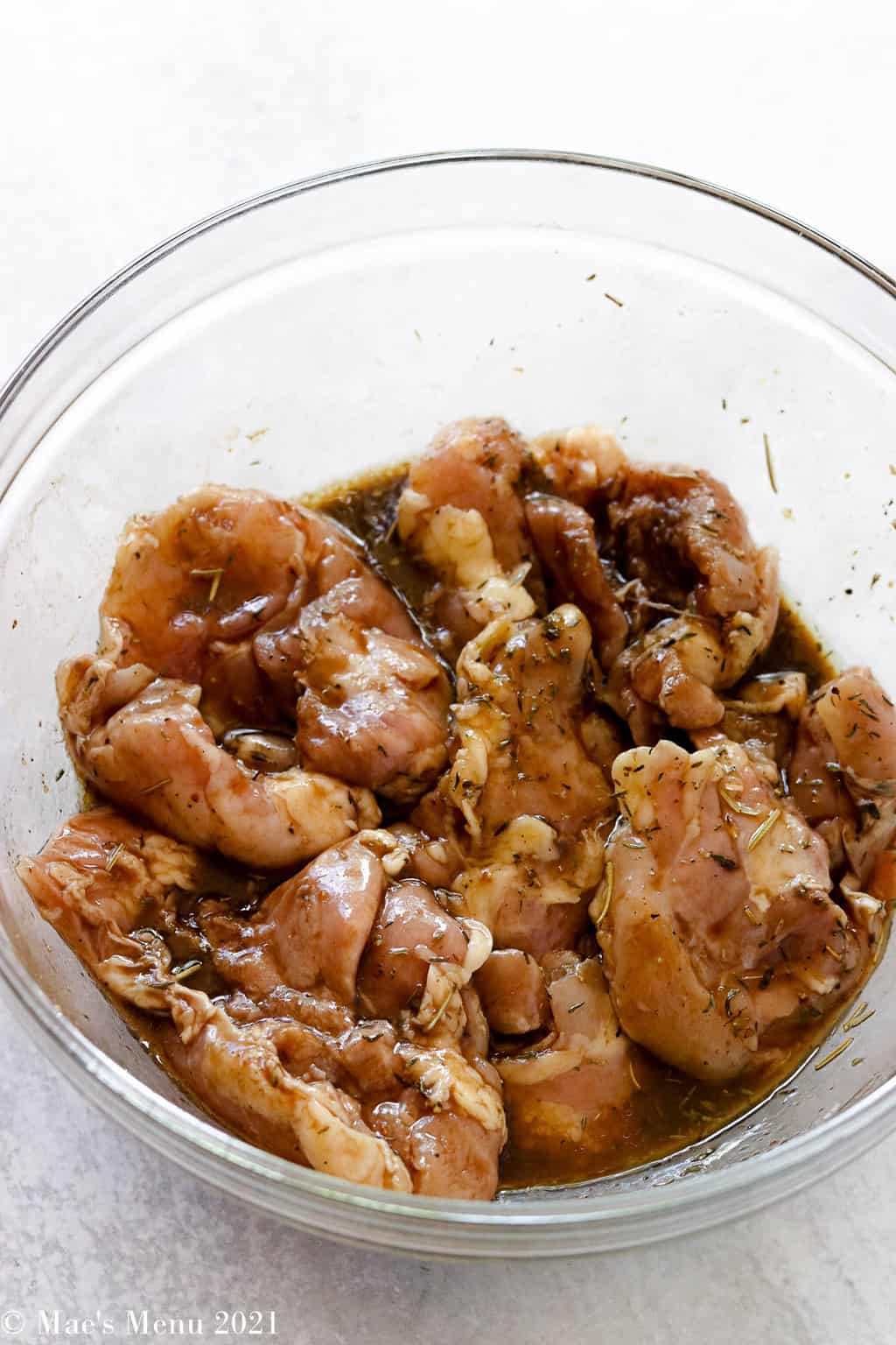 Chicken thighs marinating in a large mixing bowl