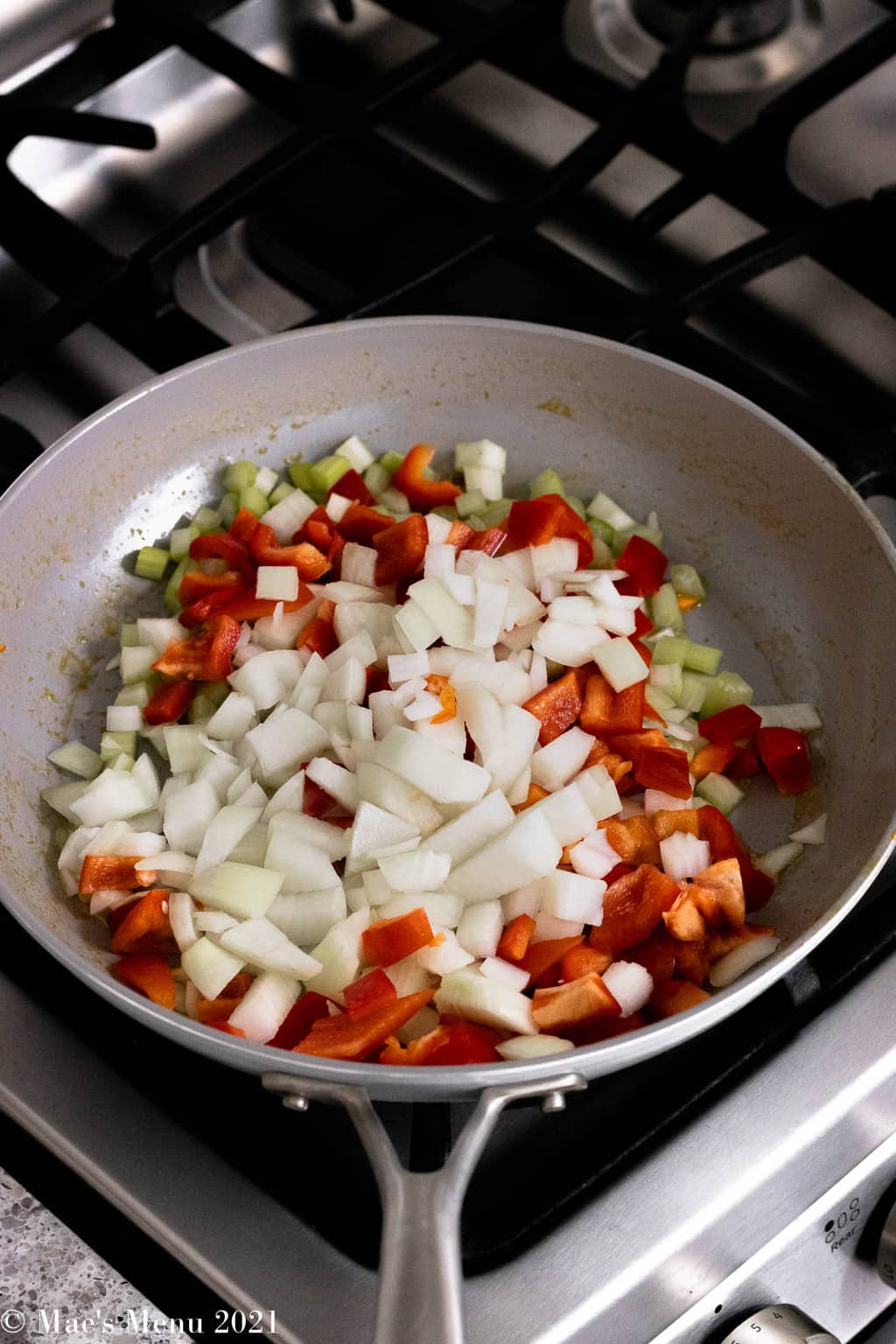 An angled shot of a saute skillet of celery, peppers, and onions.