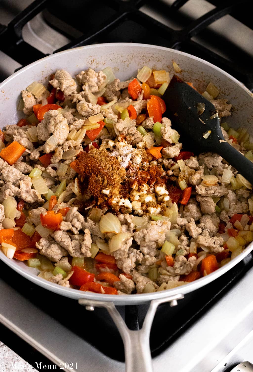 An overhead shot of a saute skillet with onions, peppers, and turkey with a ground spice mixture.