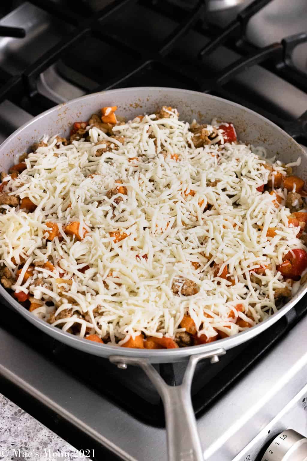 An overhead shot of a saute skillet with a ground turkey mixture with shredded mozzarella sprinkled on top.