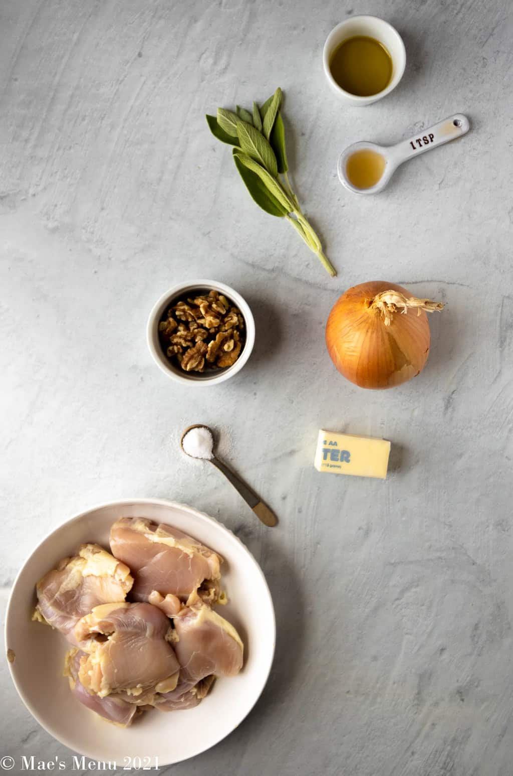The ingredients for brown butter chicken: chicken thighs, salt, butter, onions, walnuts, sage, apple cider vinegar, and olive oil.
