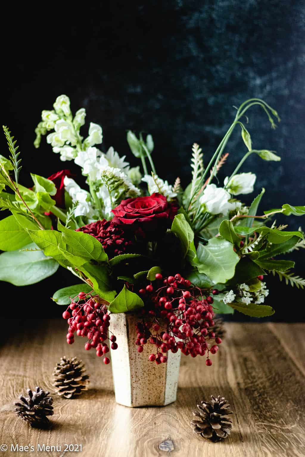 A side shot of a Christmas floral bouquet with red roses and berries.