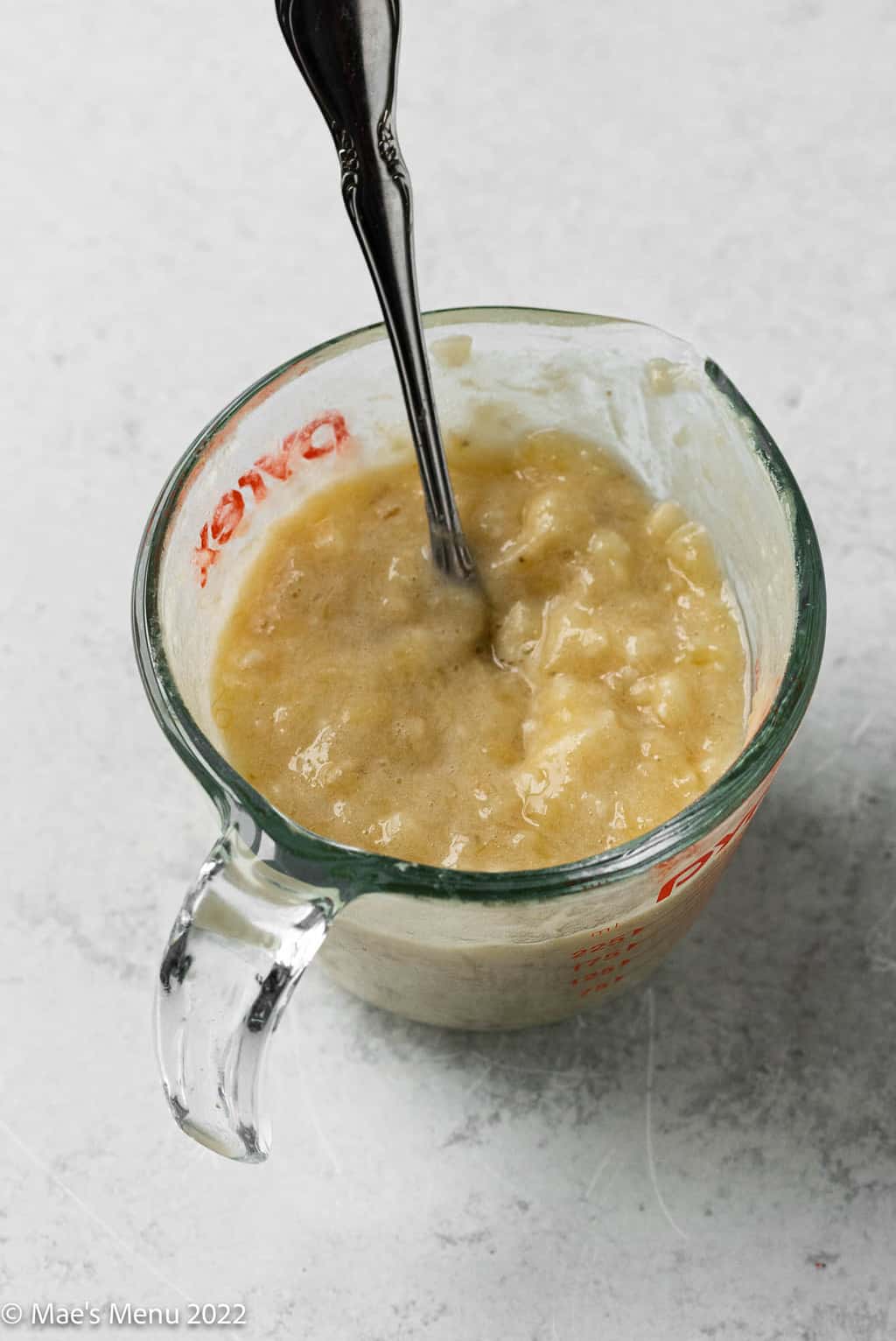 A measuring cup with mashed banana in it