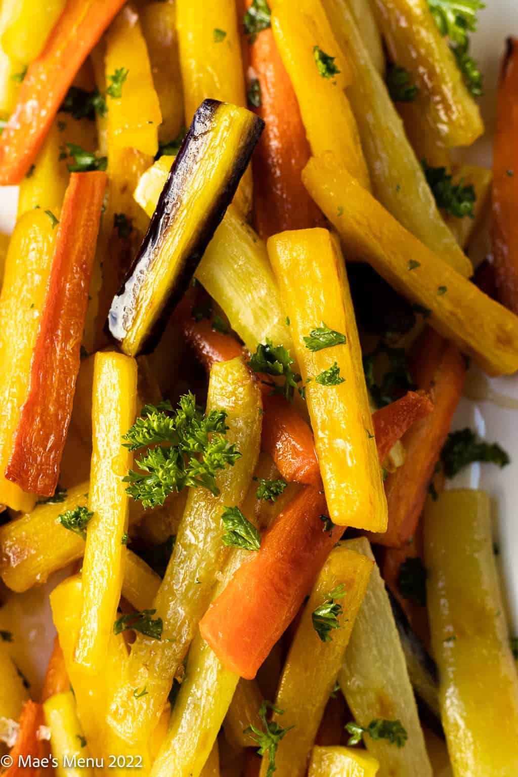 An up-close overhead shot of roasted rainbow carrots sprinkled with parsley.