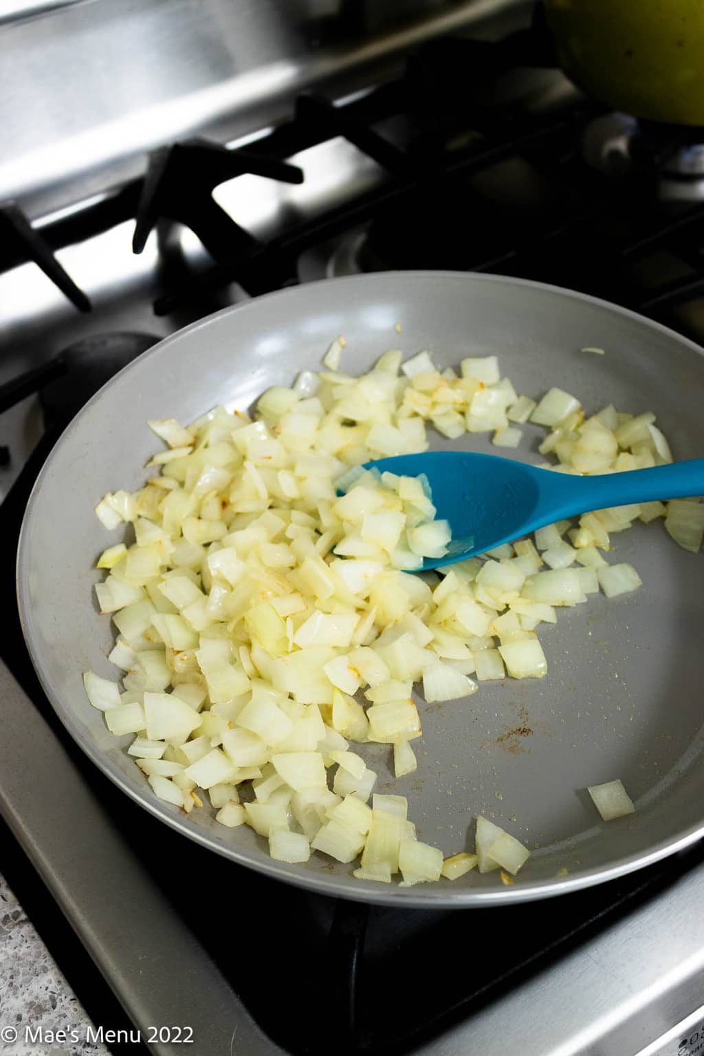 Onions sautéing on a skillet on the stove top.