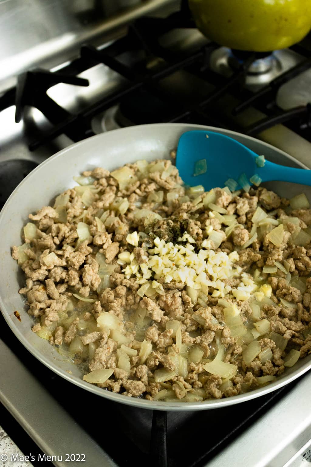 Cooked ground turkey with onions and garlic in a grey skillet.