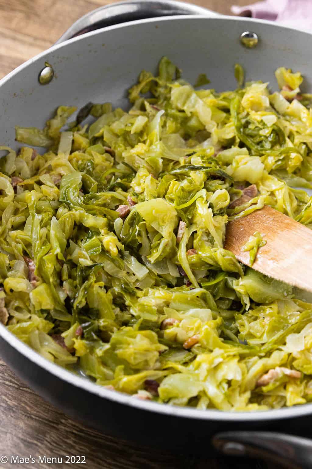 An up-close angle shot of a pan of sautéed cabbage and bacon.