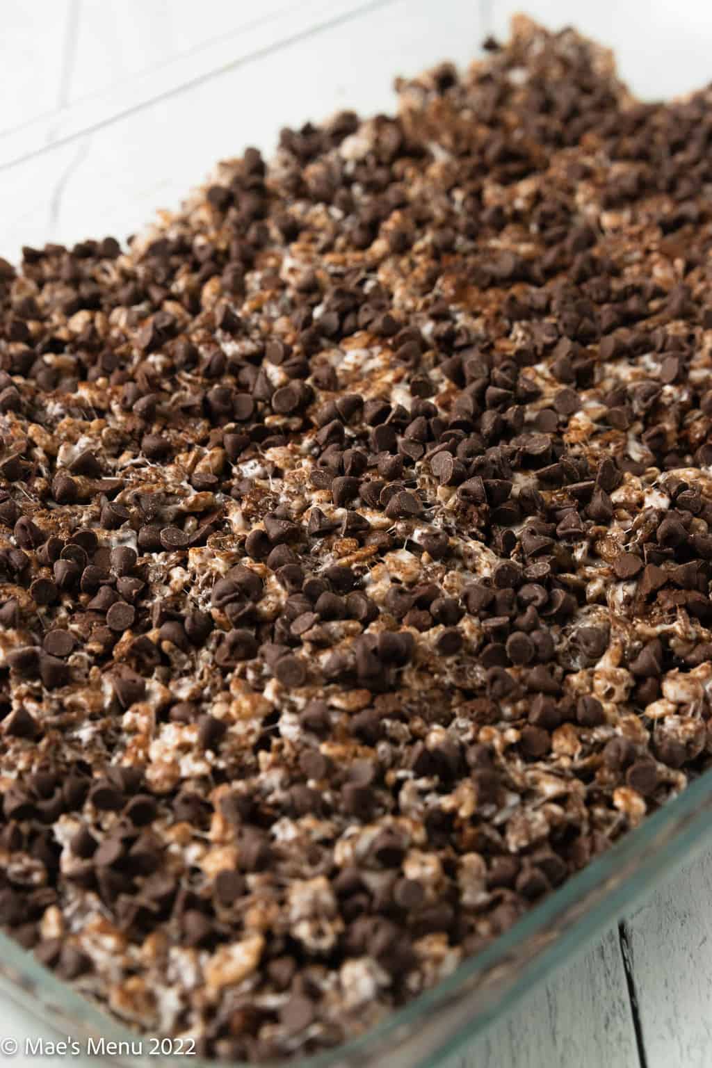 A side shot of a large tray of chocolate rice crisps sprinkled with chocolate chips.