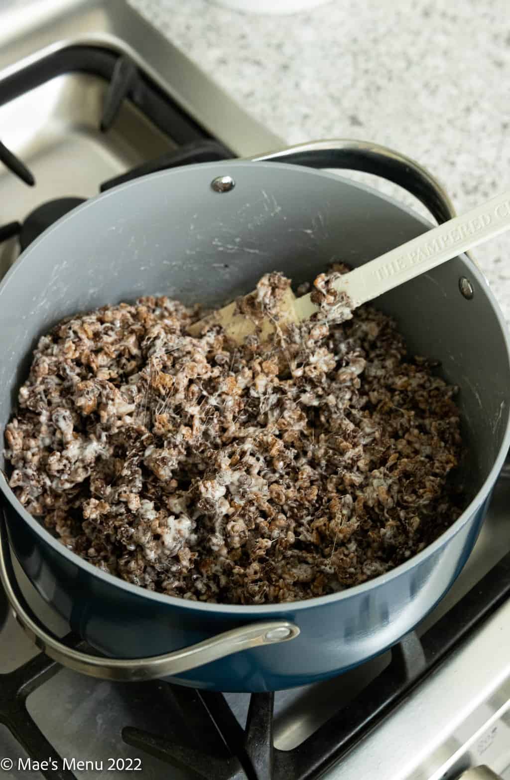An overhead shot of a pan of chocolate rice crispy batter.