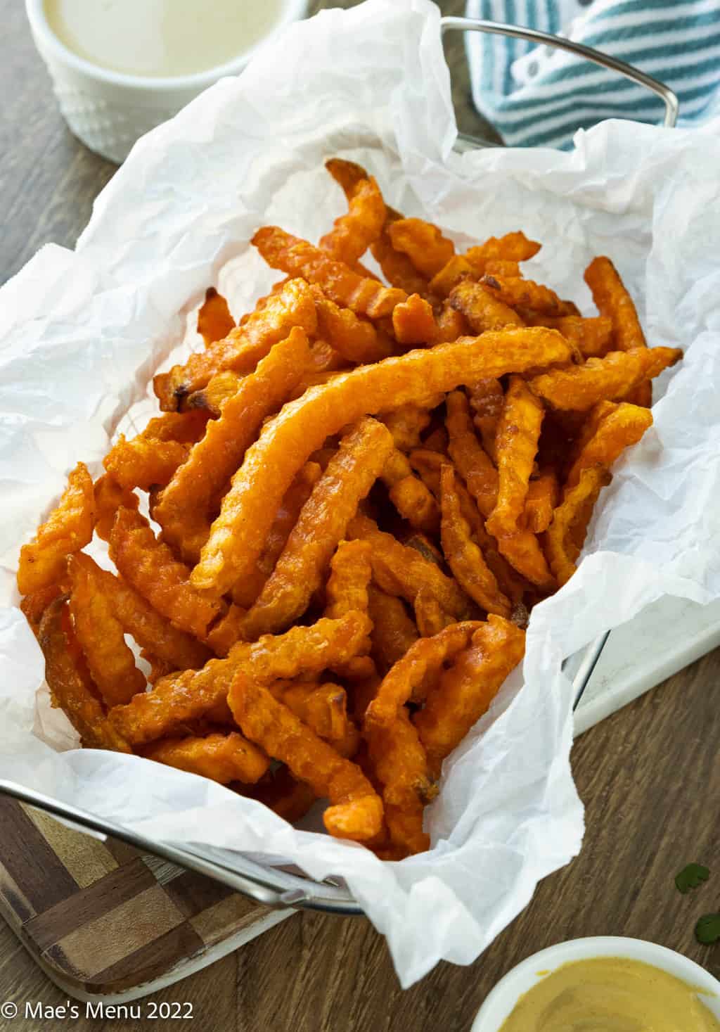 A side shot of a basket of sweet potato fries.