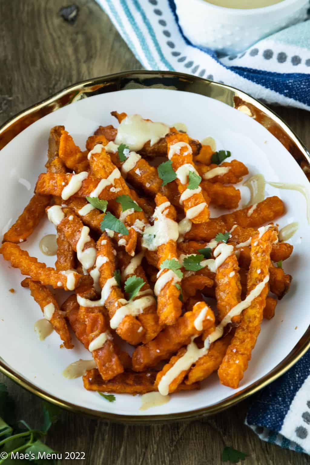 A decorative plate of air fryer sweet potato fries drizzled with honey mustard sauce.
