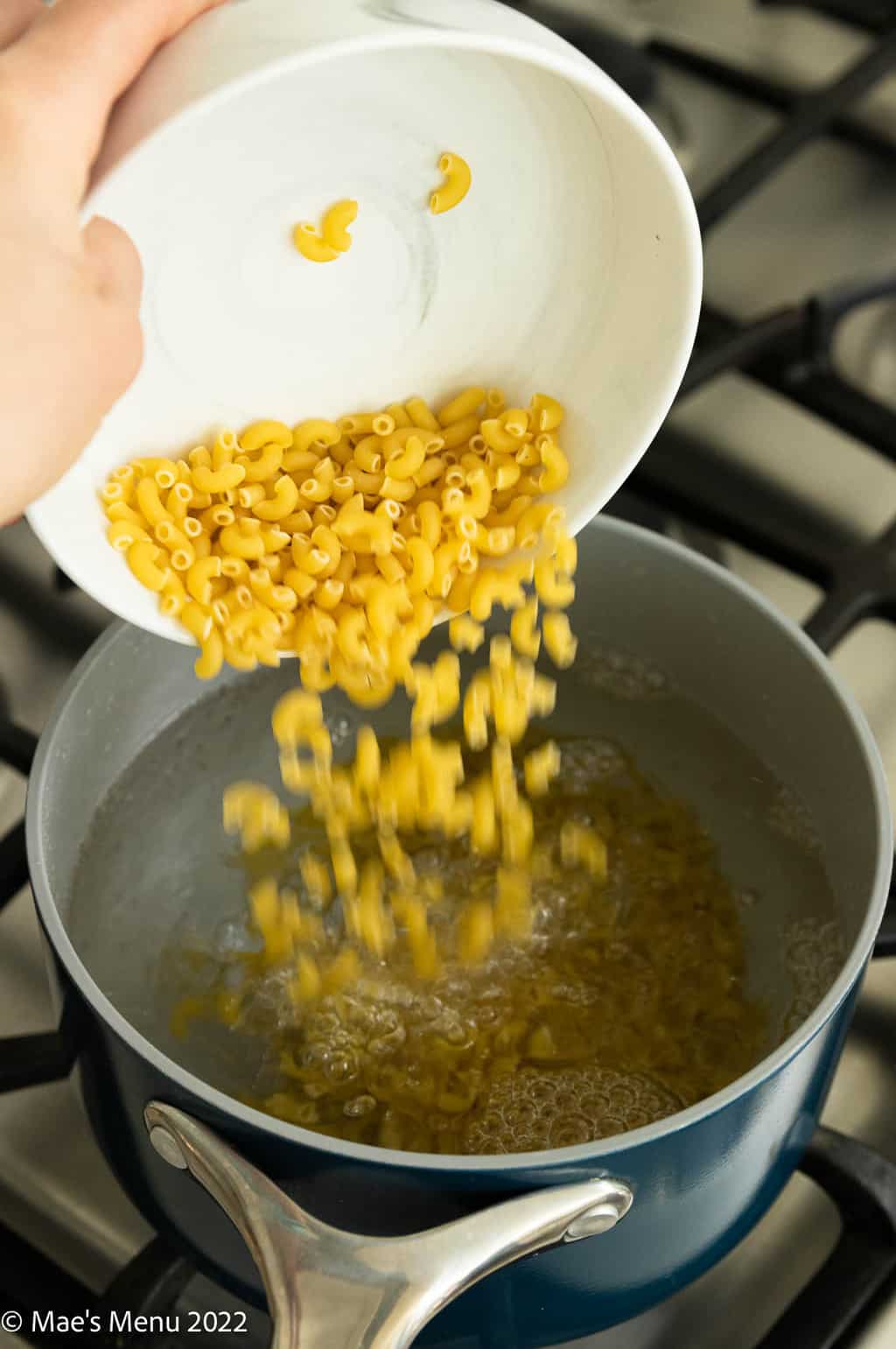 Pouring macaroni into a pot of boiling water.