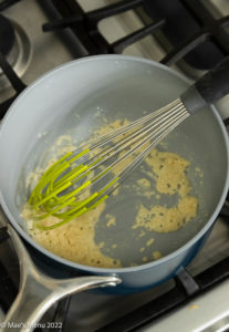 An overhead shot of a saucepan with butter and flour whisked together.