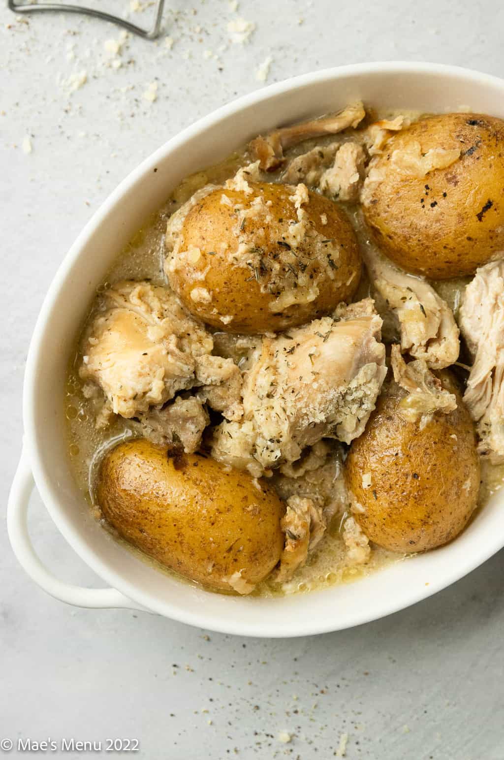 An overhead shot of bowl of chicken and potatoes in a white bowl.