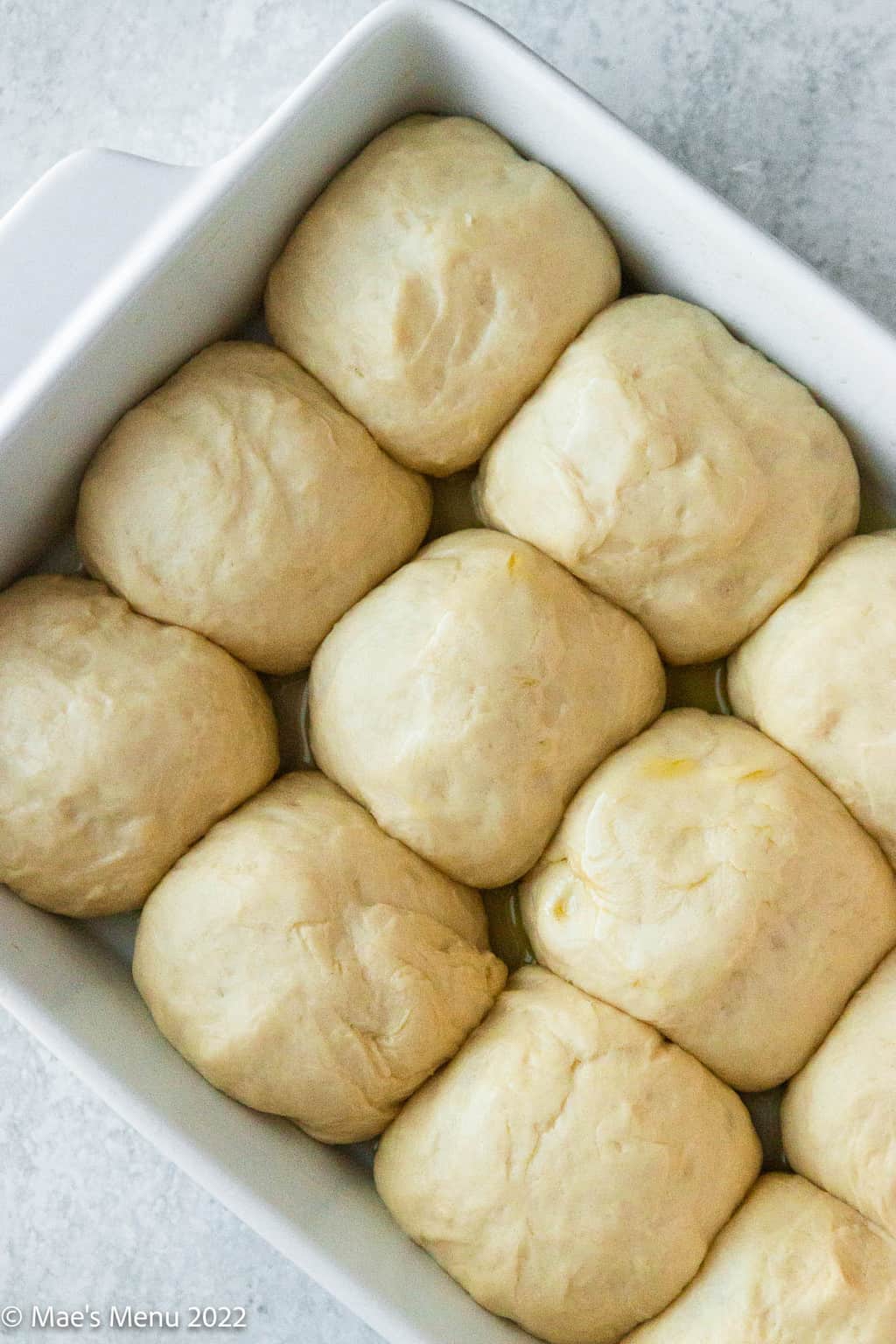 An overhead shot of a pan of proofing dinner rolls