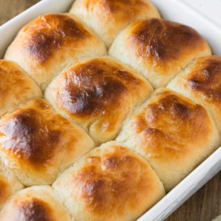 A side shot of a white pan of sweet dinner rolls.