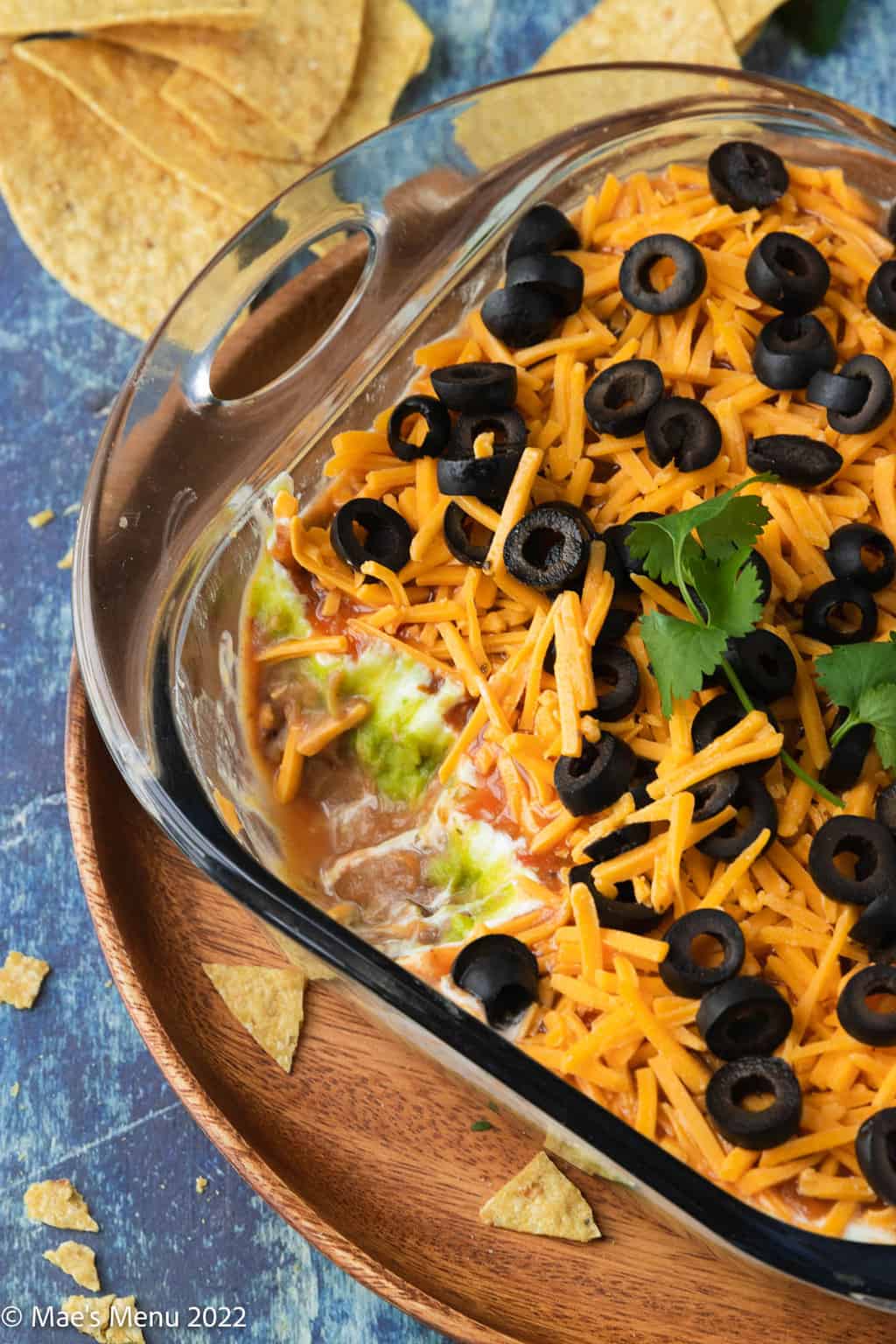 An overhead shot of a pan of 5 layer bean dip with a large scoop taken out of it.