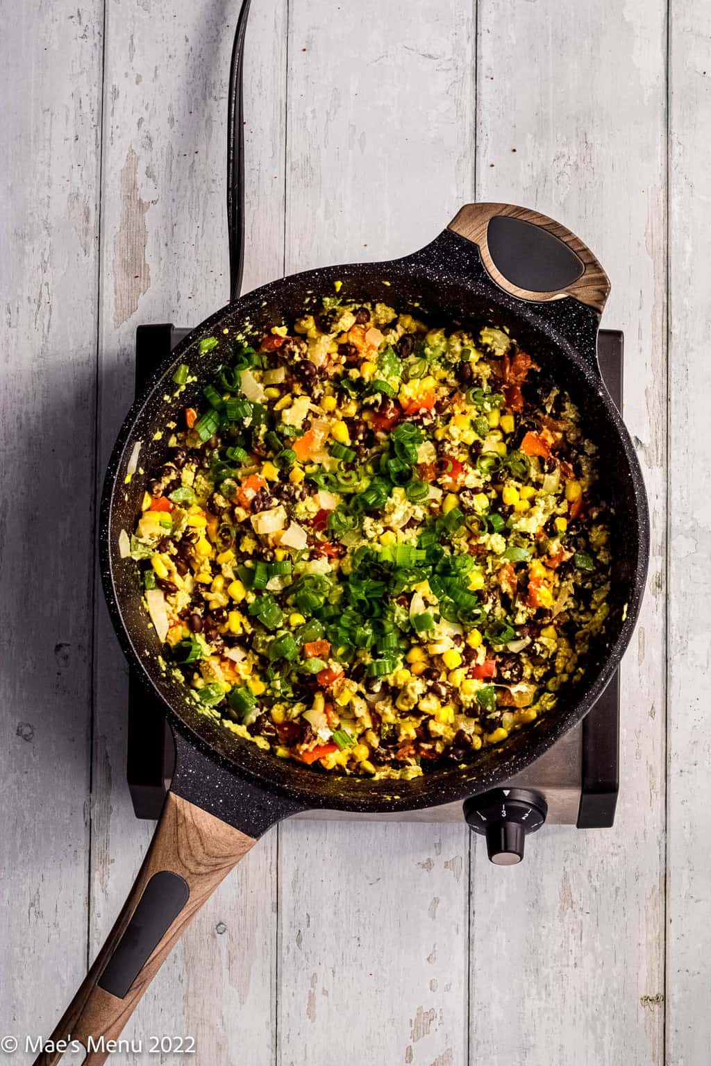 An overhead shot of a skillet of veggies, beans, and eggs.