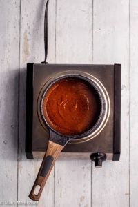 An overhead shot of a small pot of red enchilada sauce.