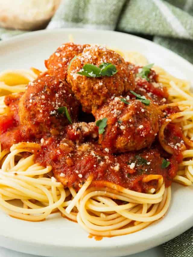 A side shot of a white plate of instant pot spaghetti and meatballs.