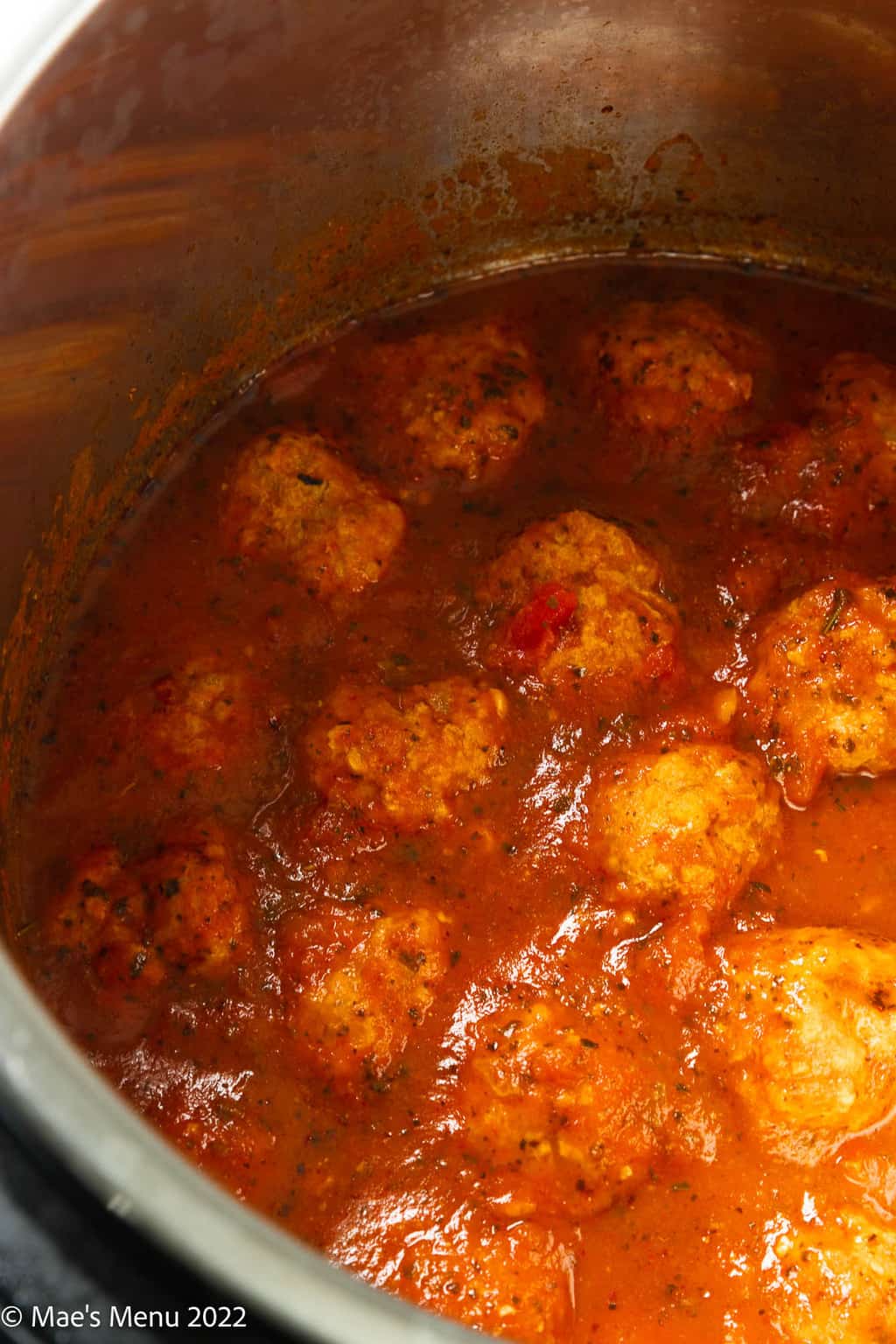 An up-close shot of meatballs in pasta sauce in a bowl of a pressure cooker.