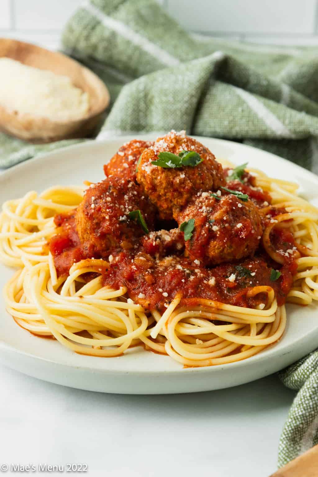 An up-close side shot of a white plate of instant pot meatballs dished over spaghetti.