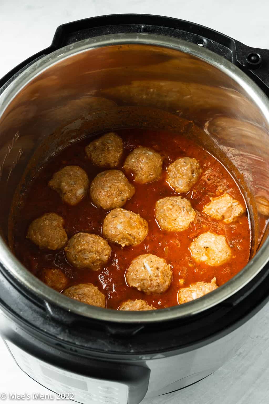 An instant pot of turkey meatballs resting in tomato sauce.