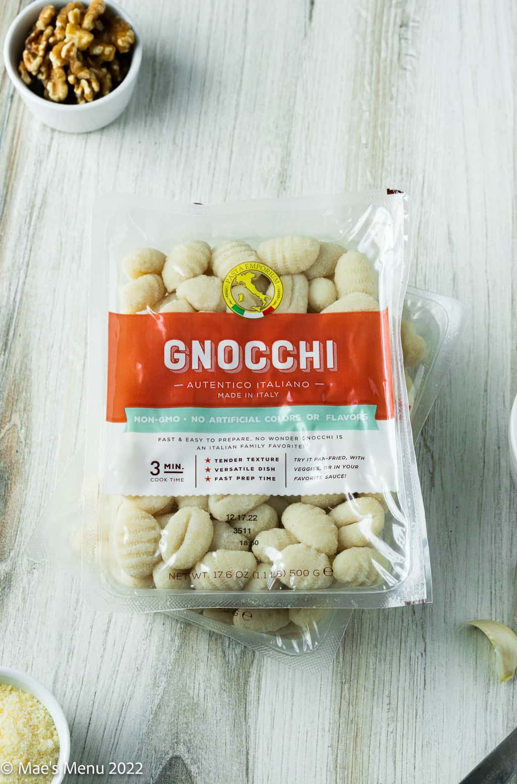 A package of potato gnocchi and small dish of walnuts.
