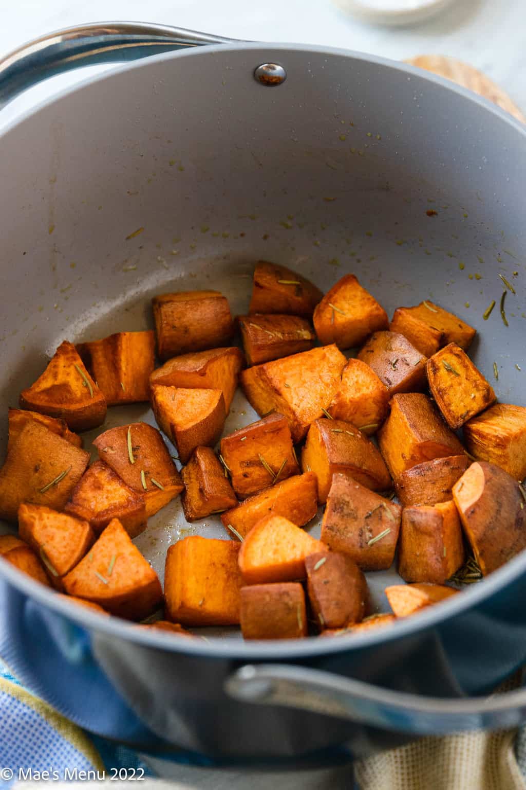 An angled shot of a dutch oven of roasted sweet potatoes.