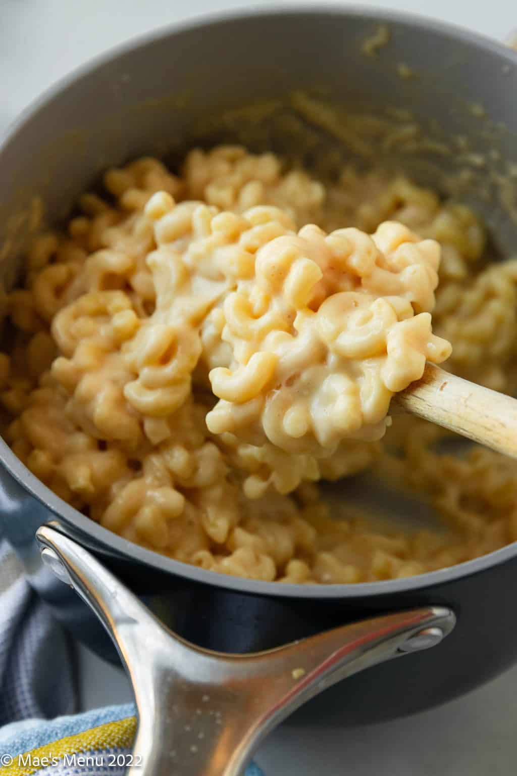 Scooping smoked gouda mac and cheese out of a saucepan.